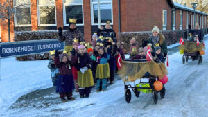 Børn og personale står foran skiltet med Børnehuset Tusindfryd